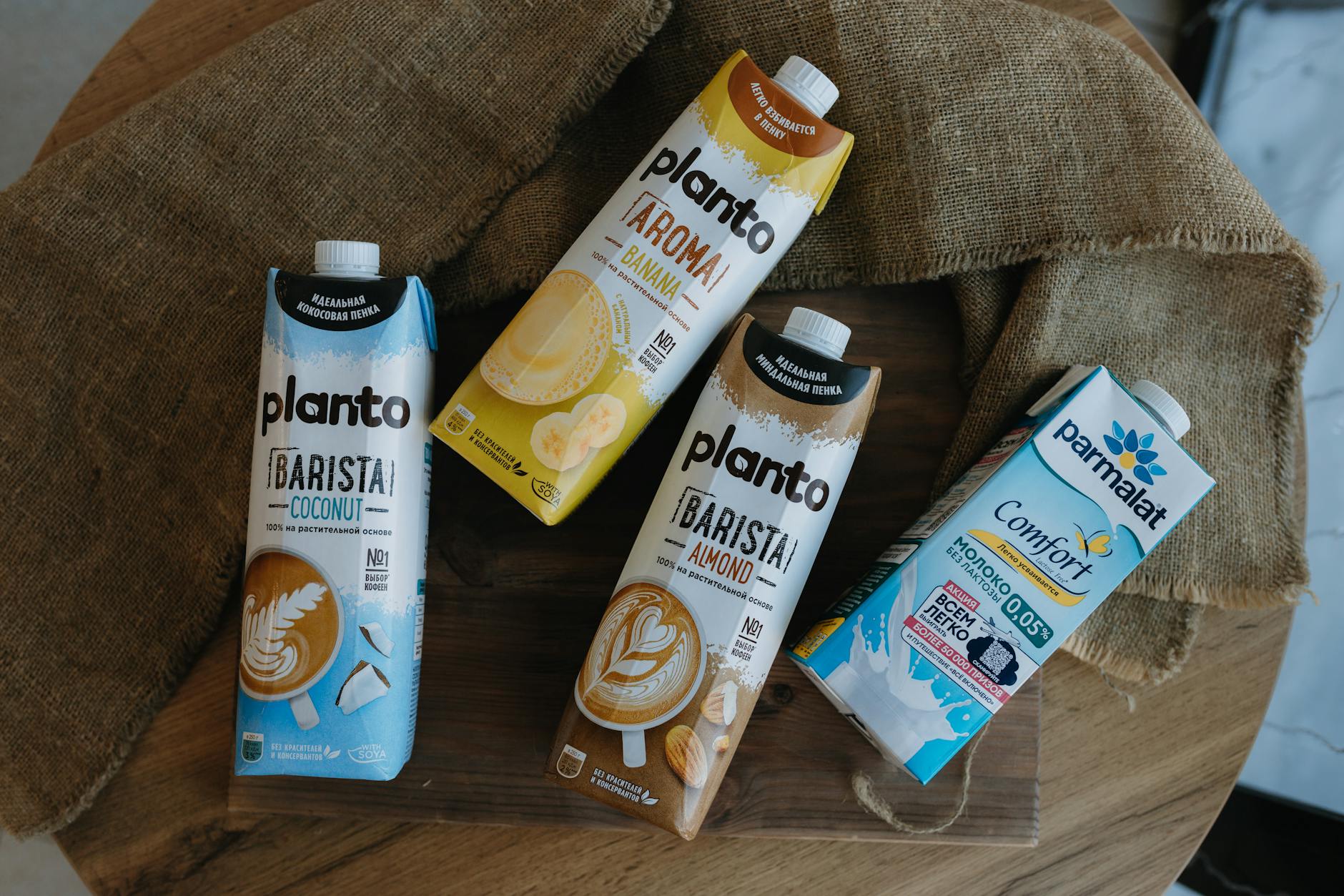 Top view of plant-based and dairy milk cartons on a rustic wooden table