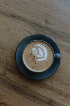 Top view of a cappuccino with latte art on a wooden table. Perfect for cafe and coffee themes.