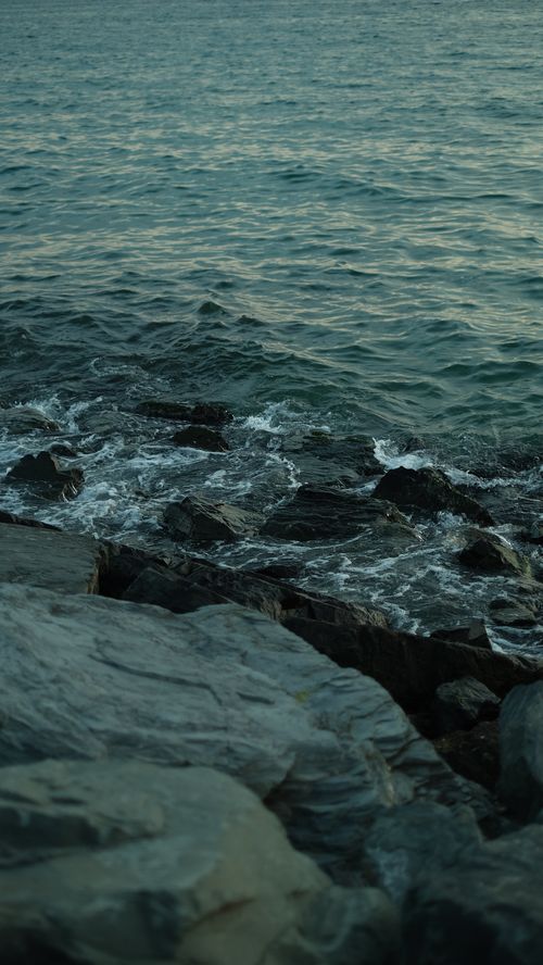 Free Peaceful coastal scene with dark rocks and gentle ocean waves, perfect for nature themes. Stock Photo