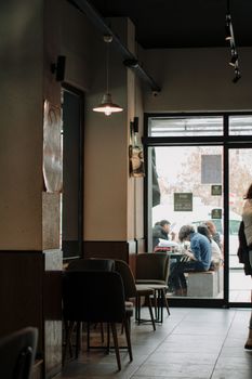 Warm café interior with natural light and outside view of people dining. Perfect for urban lifestyle themes.
