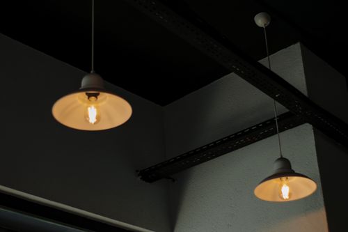 Free Two industrial-style pendant lamps hanging from a metal-beamed ceiling with a warm glow. Stock Photo