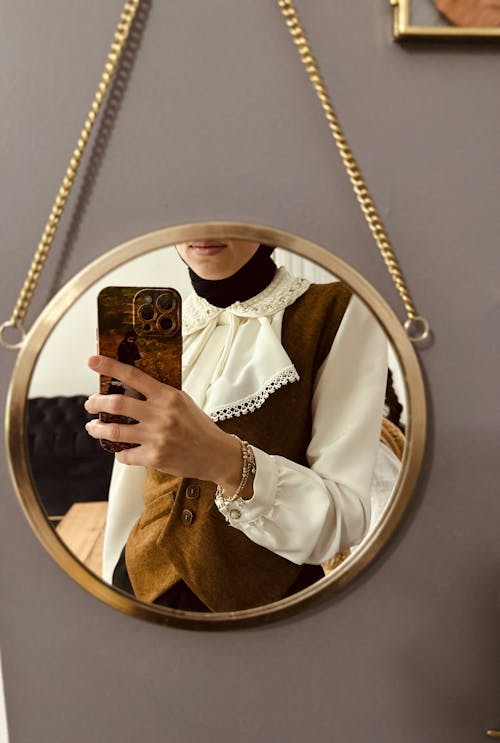 Reflection of Woman in Vest Taking Pictures in Mirror