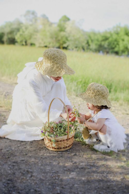 Free A mother and daughter in white dresses picking flowers on a summer day in a peaceful meadow. Stock Photo