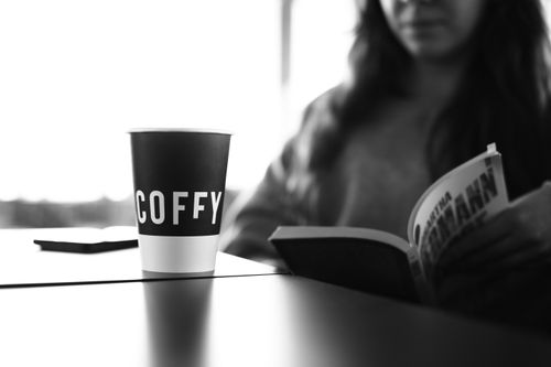Free A woman enjoys a coffee and book in a tranquil black and white setting. Stock Photo