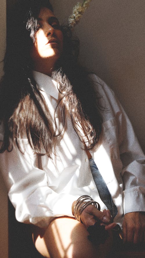 A woman in a white shirt and tie sitting on a chair