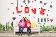 Two women sitting on a sofa, smiling with love-themed decor in Ciudad de México.