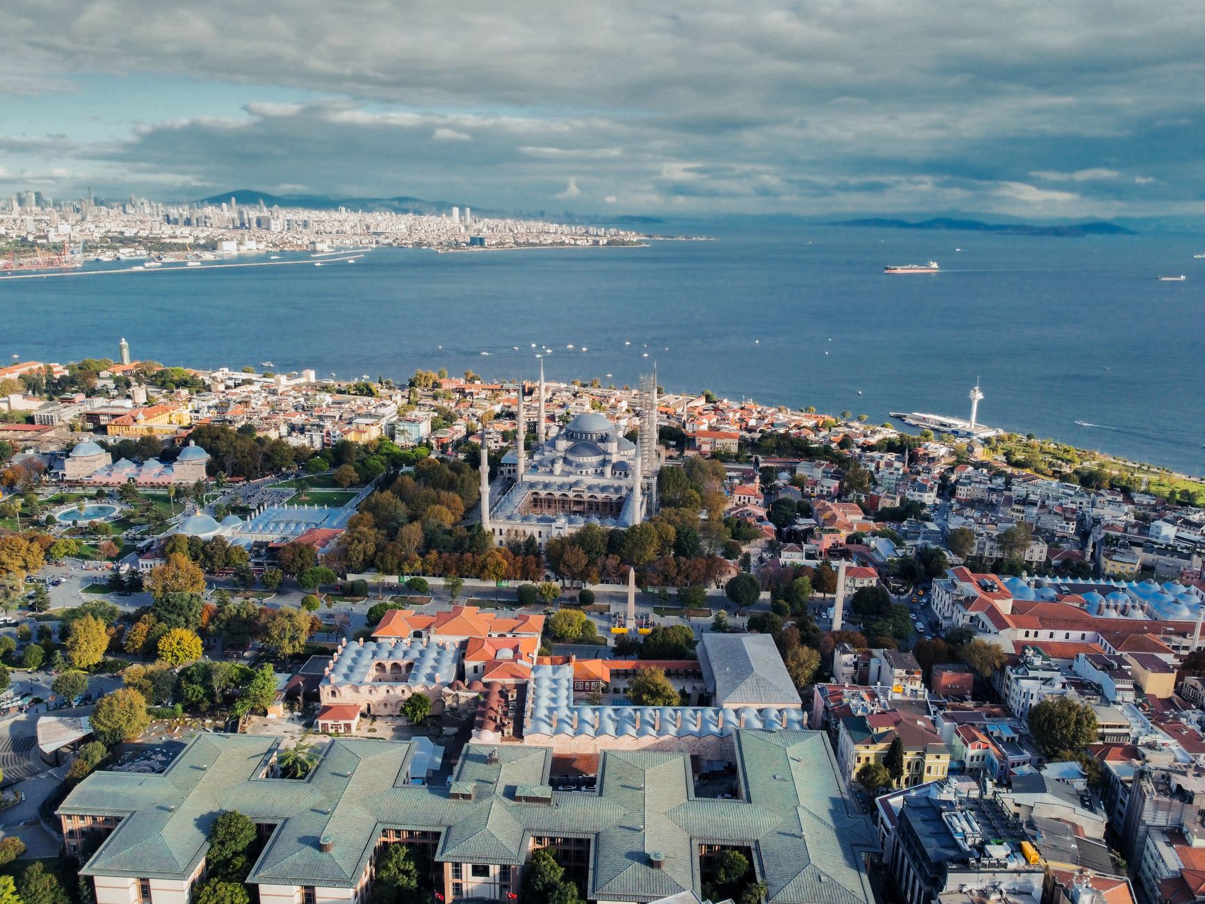 Drone shot capturing the iconic Blue Mosque and Istanbul's vibrant cityscape along the Bosphorus Sea.