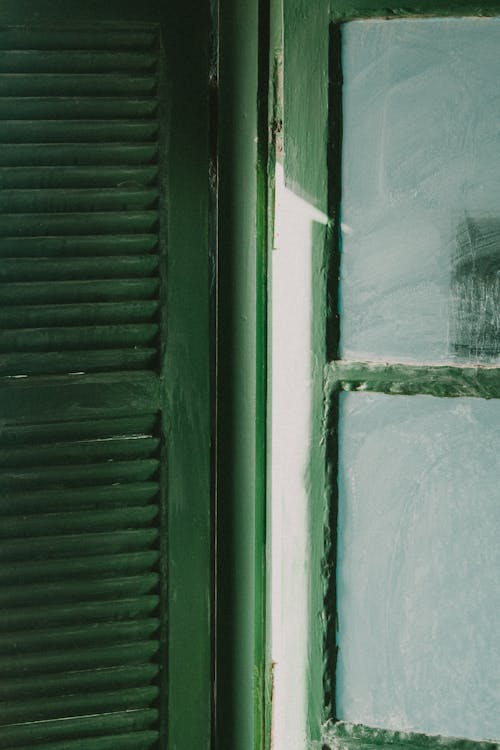 A green window with shutters and a white door