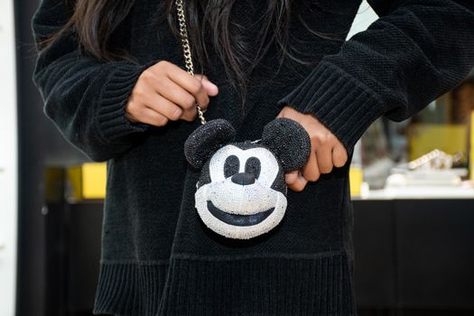 Stylish woman in black holding a Mickey Mouse-themed handbag in Islamabad.
