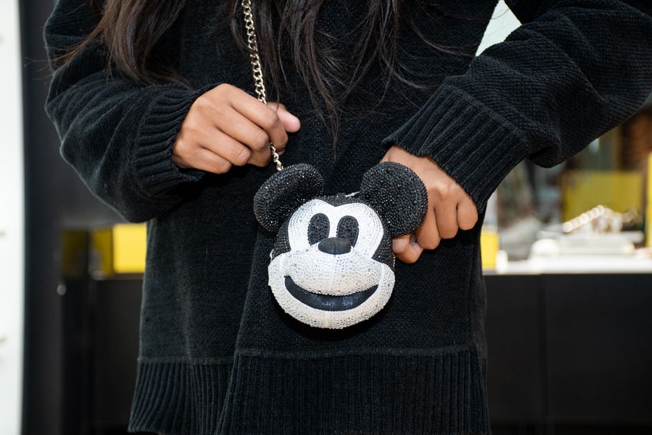 Stylish woman in black holding a Mickey Mouse-themed handbag in Islamabad.