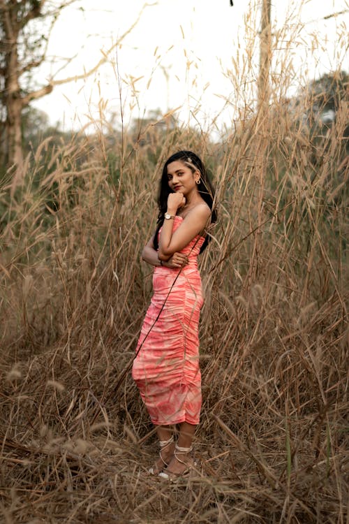 A woman in a pink dress standing in tall grass
