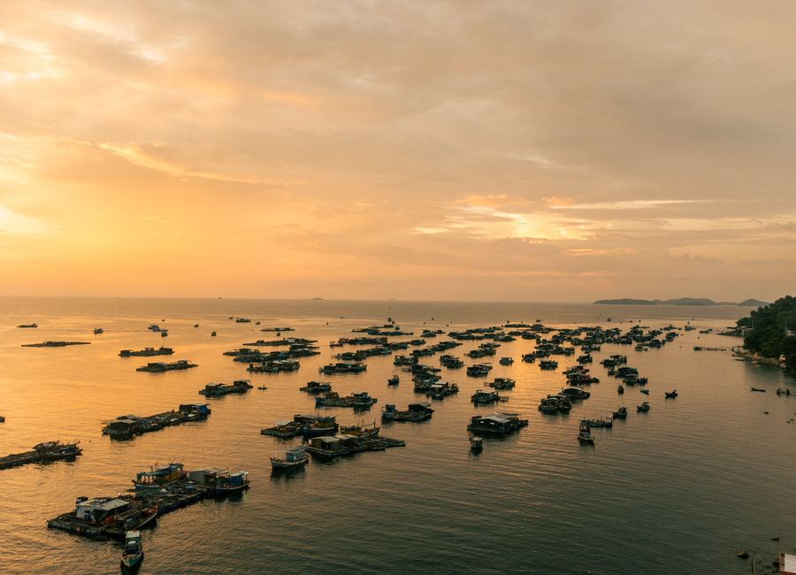 Serene aerial view of houseboats on golden waters during sunset in Kiên Giang, Vietnam.