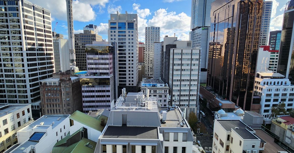 A vibrant view of Auckland's modern skyline featuring the iconic Sky Tower under a clear blue sky.