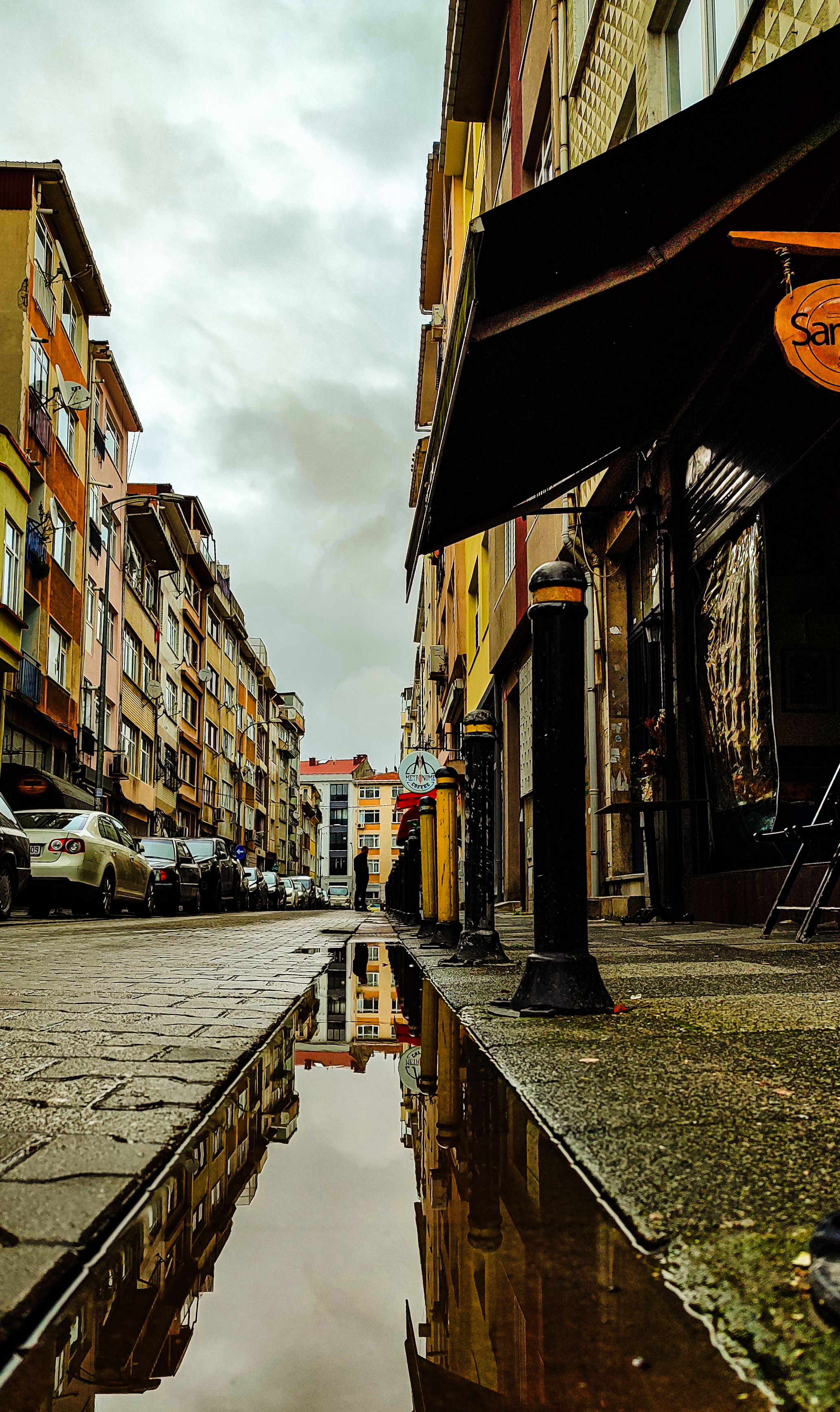 Puddle reflection on an urban street in Istanbul, showcasing colorful residential buildings.