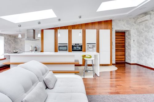 Free Bright modern kitchen with white and wood elements, featuring a cozy sofa and sleek wooden floor. Stock Photo