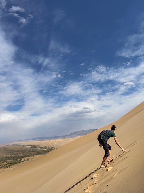 Man Climbing Barren Hill on Desert