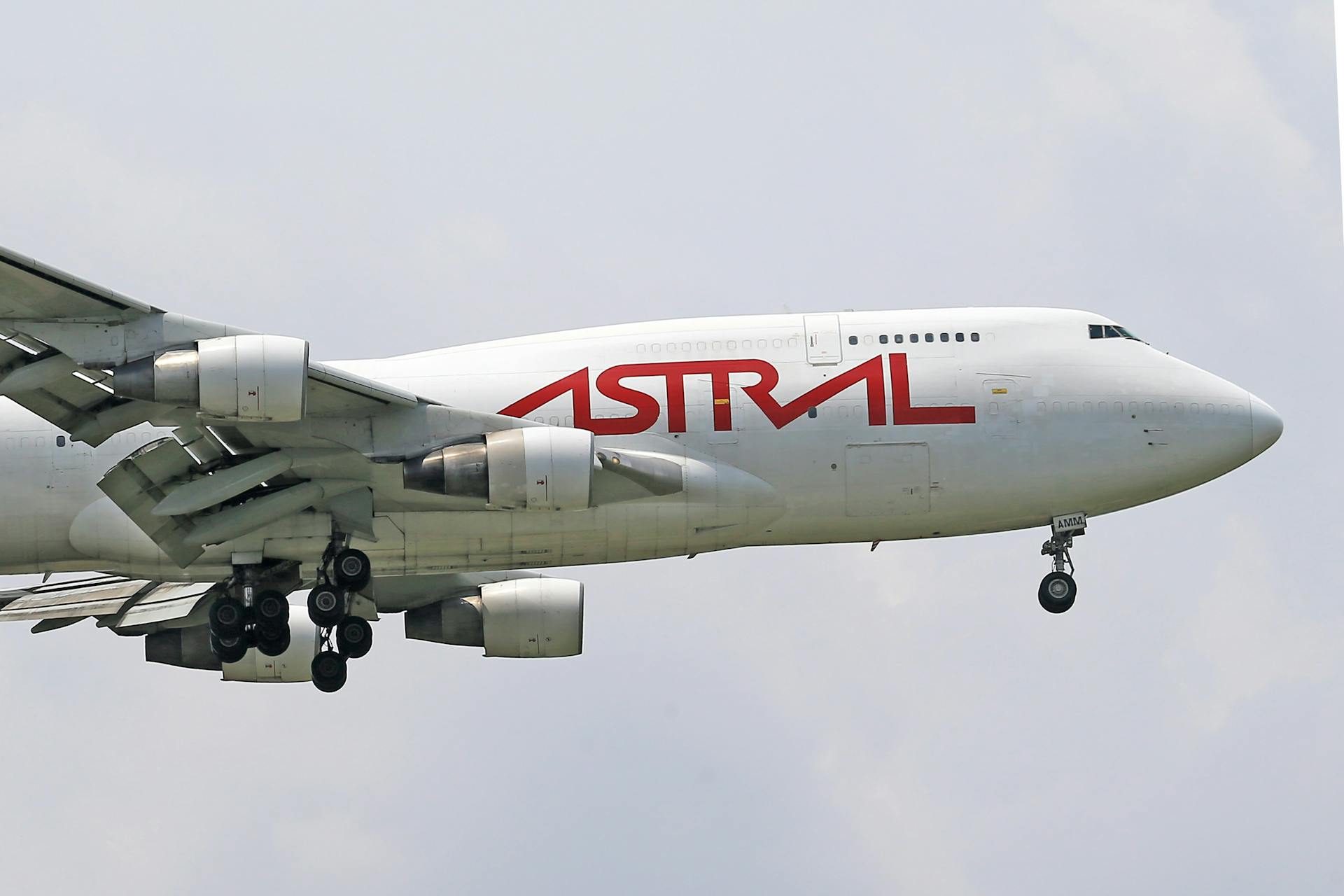 Close-up view of Astral Aviation cargo plane mid-flight against cloudy sky.