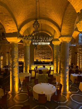 Luxurious restaurant setting with columns, chandeliers, and elegant table arrangements.