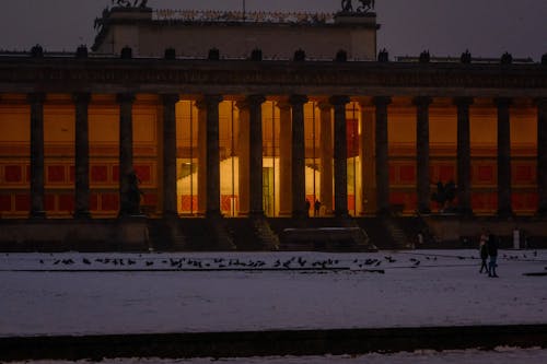 The building is lit up at night with snow on the ground