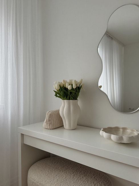 Elegant minimalist interior featuring a white tulip vase and artistic mirror.