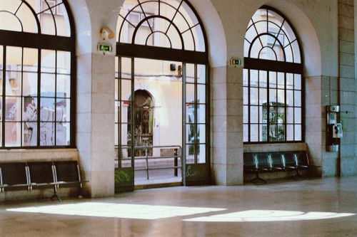 Free Arched windows and seating in Lisbon station hall with urban view outside. Stock Photo