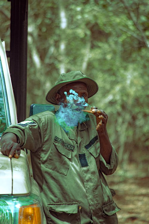 Man in Green Ranger Uniform Smoking Pipe in Forest