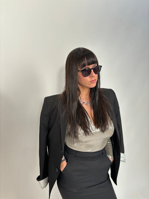 A woman in a suit and sunglasses posing for a photo