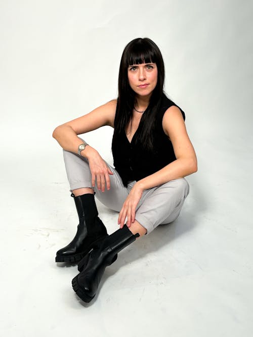 Woman Sitting in Black Vest and Boots