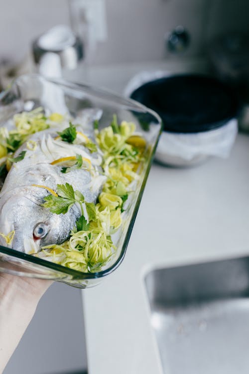 Peixe num tabuleiro de vidro  temperado com limão, salsa e alho francês