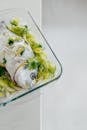 Peixe num tabuleiro de vidro  temperado com limão, salsa e alho francês
