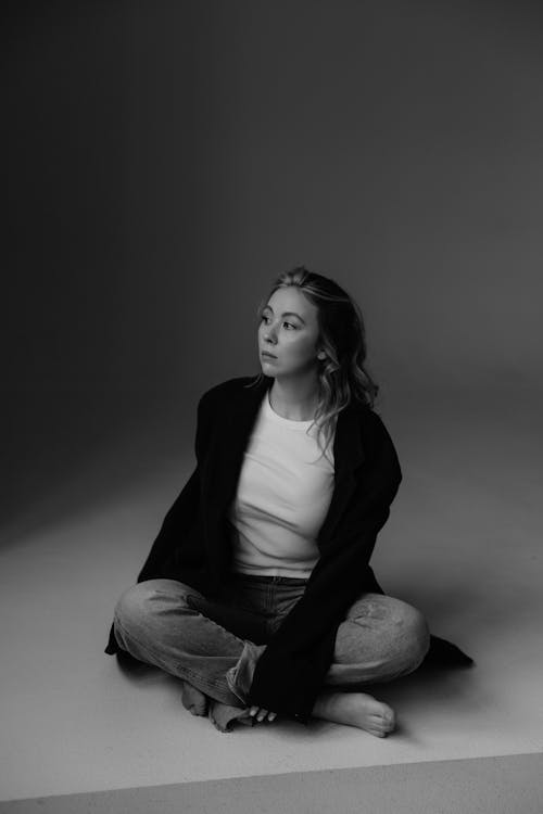 Woman in Suit Jacket Sitting in Black and White