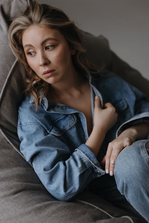 A woman in a denim jacket sitting on a couch