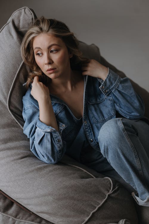 Woman in Jean Shirt and Jeans Sitting on Pillow