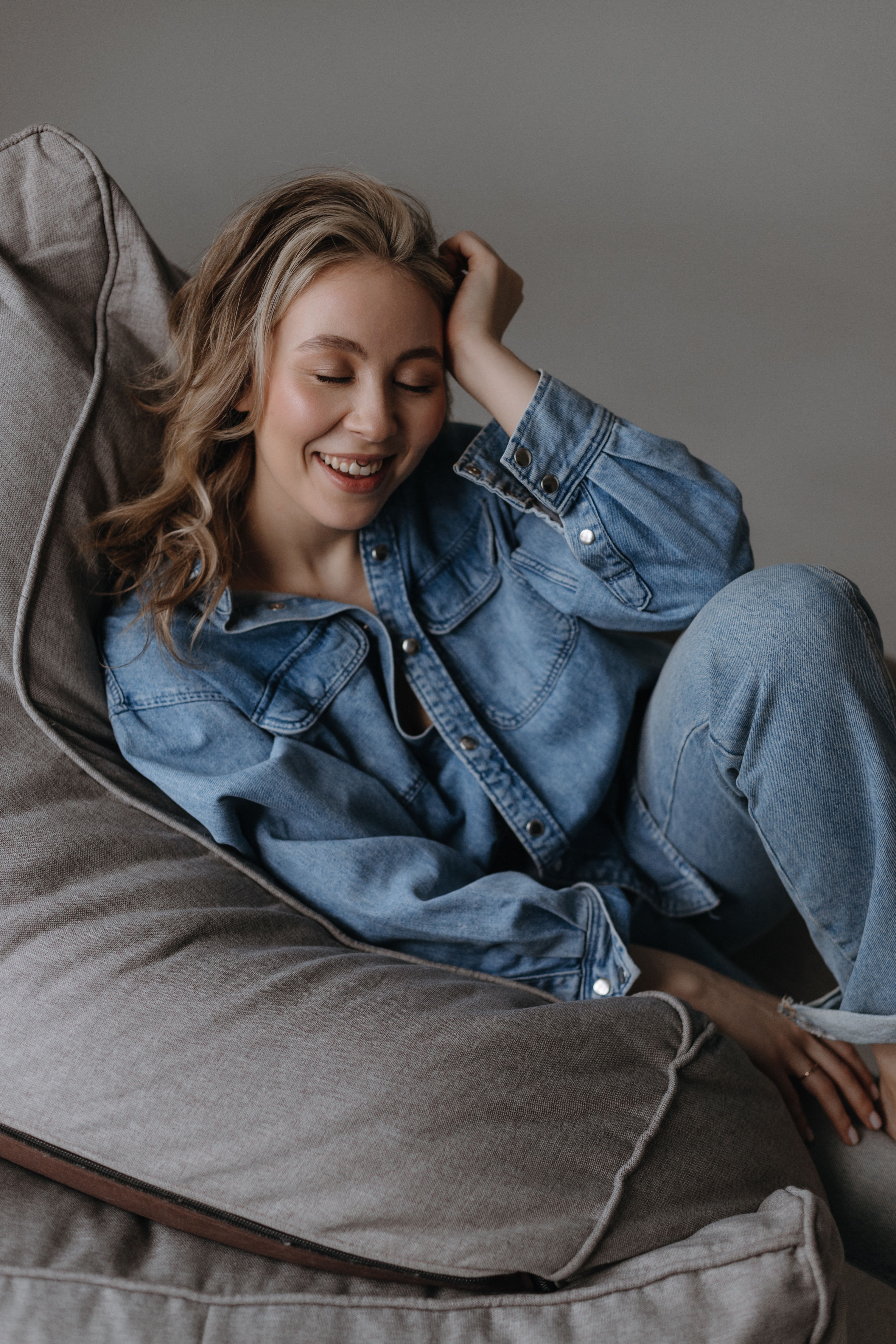 Smiling Woman with Closed Eyes Sitting on a Bean Bag · Free Stock Photo