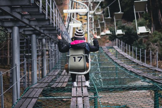 Person enjoying a peaceful ski lift ride with a playful gesture, embracing a winter adventure.