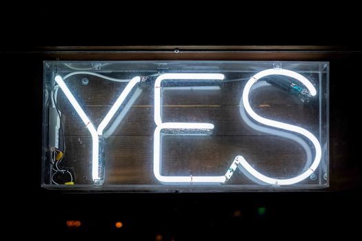 Close-up of a glowing neon 'YES' sign in a dimly lit setting, emitting a bright vibe.