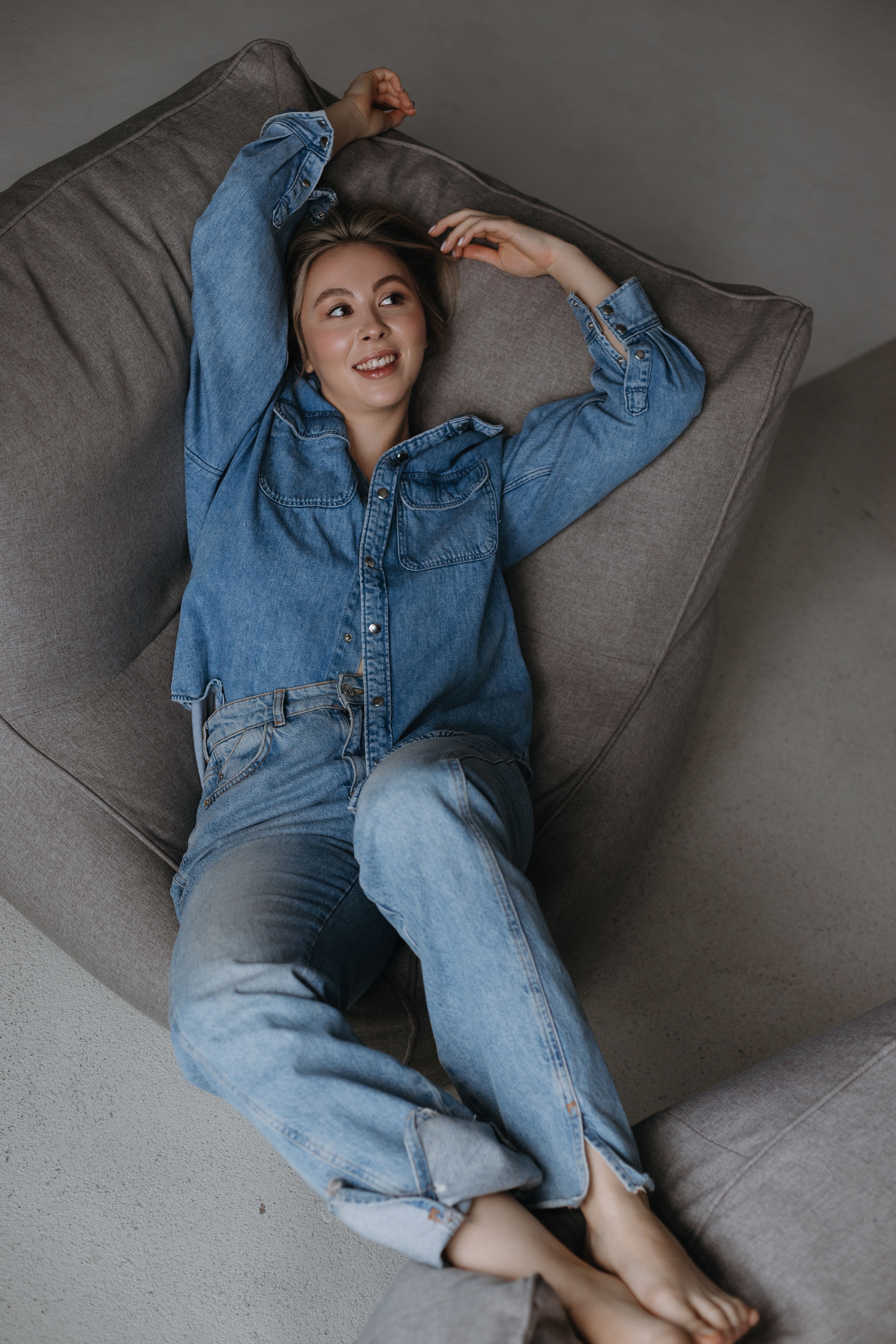 Smiling Model in Denim Clothes Lying on a Gray Bean Bag Chair · Free ...