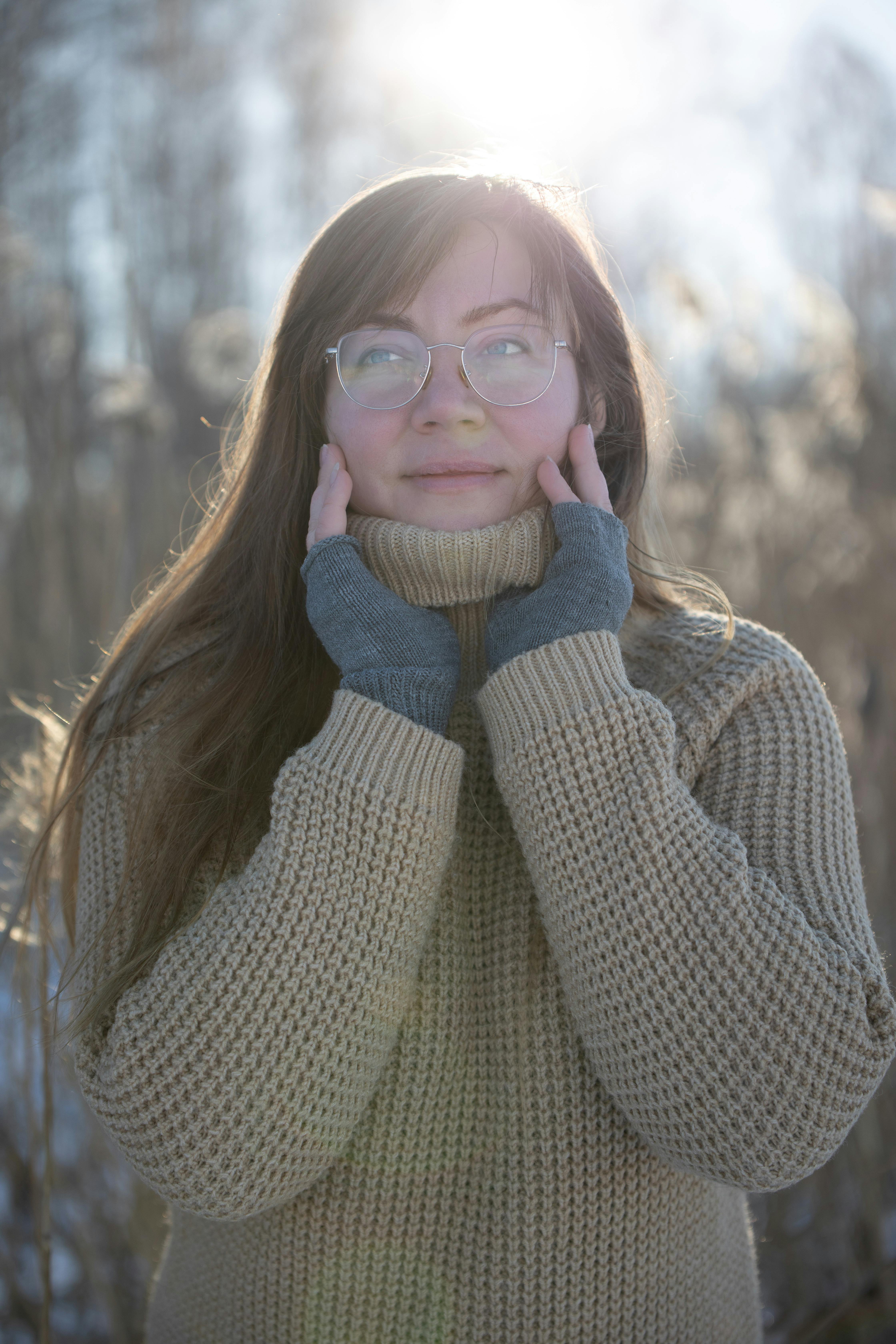A cheerful woman in a turtleneck sweater enjoys the winter sun outside. Perfect for fashion and lifestyle themes.