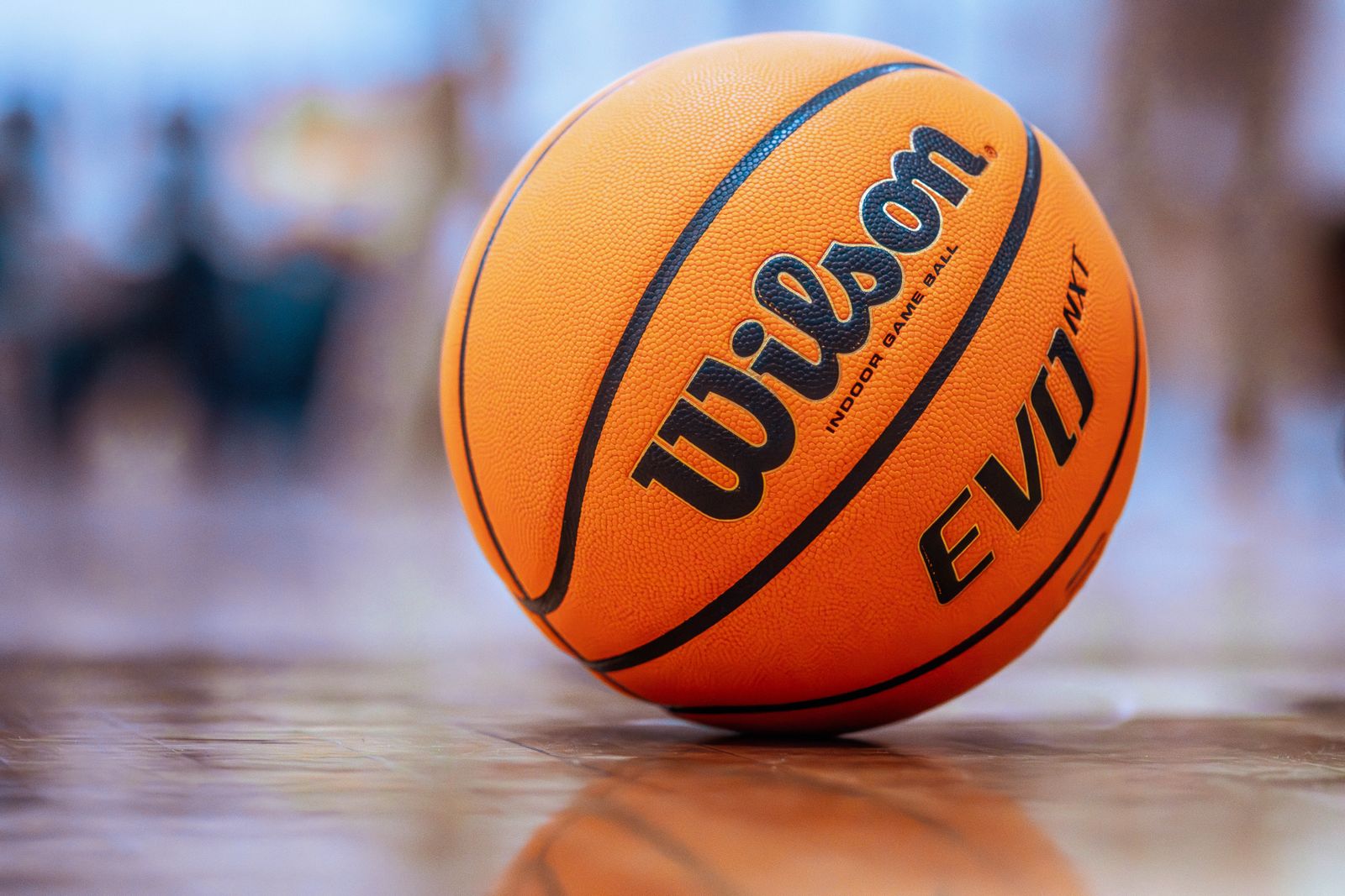 Bola de basquete laranja em close sobre o piso de madeira polida do ginásio