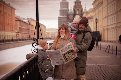A family is reading a newspaper on a bridge