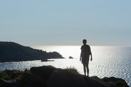 A person standing on a rock looking out to the ocean