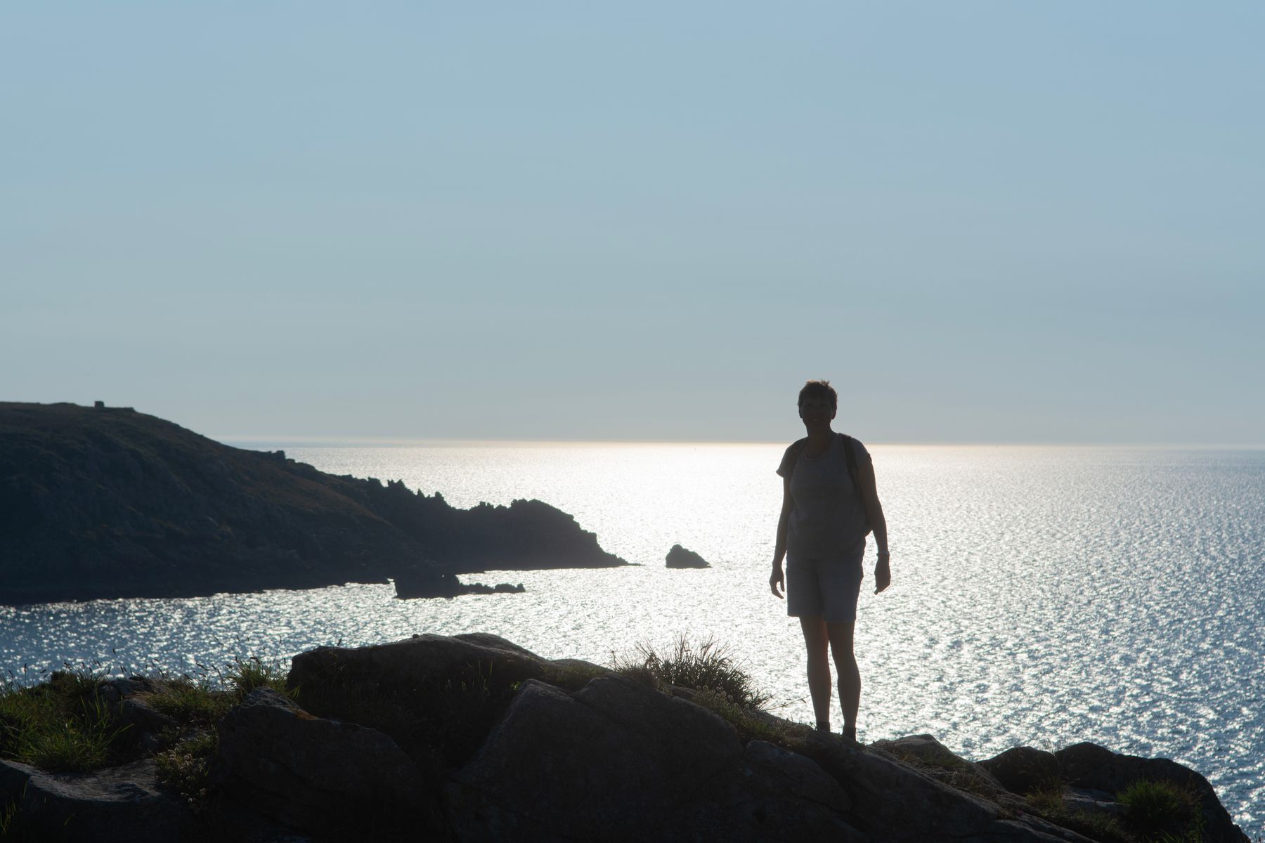 Walker on a coastal headland above a bright sea, photo by Jan van der Wolf on Pexels