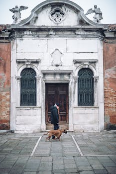 A person walks their dog near the Oratorio Ex Ospizio Briati in Venice, Italy, showcasing beautiful architecture.