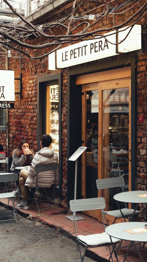 Free Charming urban café entrance with people enjoying a leisurely chat outdoors. Stock Photo