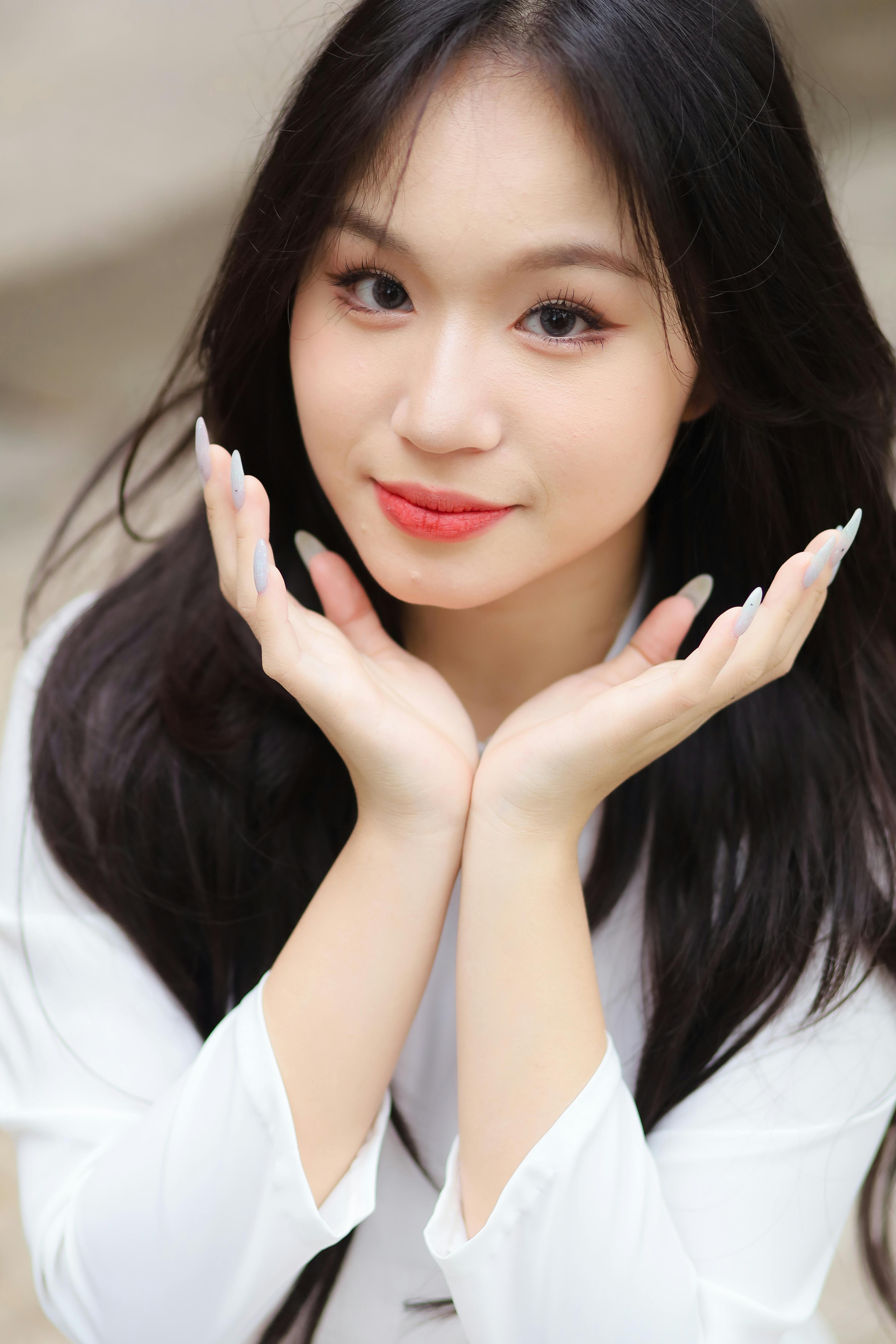Portrait of a young woman with long black hair, subtle makeup, and red lips in a relaxed pose.