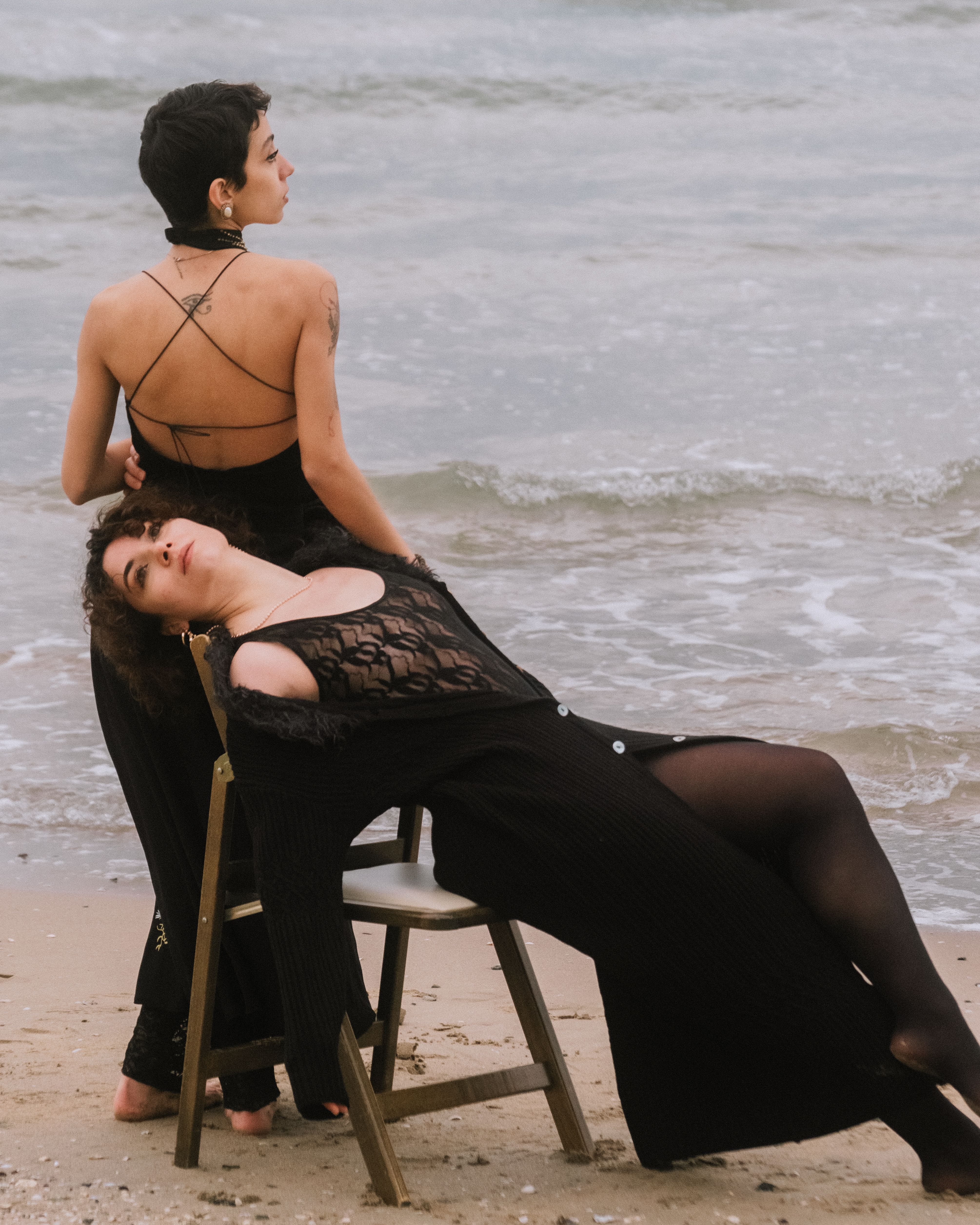 Two women in bohemian style dresses relax on a beach chair by the sea in Şile, İstanbul.
