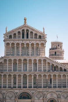 Front view of Pisa Cathedral with the Leaning Tower in the background, showcasing Romanesque architecture.