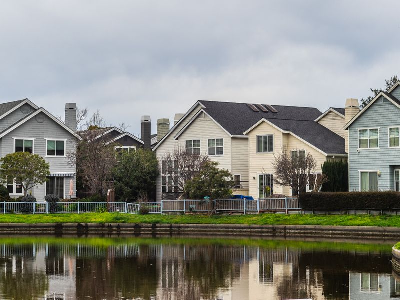 Houses reflected in a calm river lined with greenery