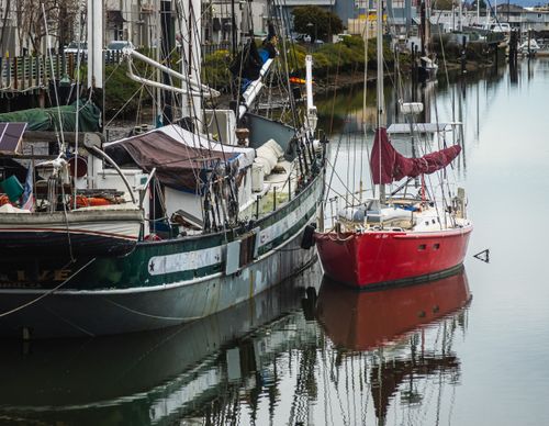 Free A serene scene of sailboats moored along a calm canal in a quaint town. Stock Photo