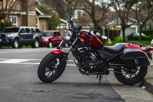 Free A striking red motorcycle parked on an urban street corner showcasing urban lifestyle. Stock Photo